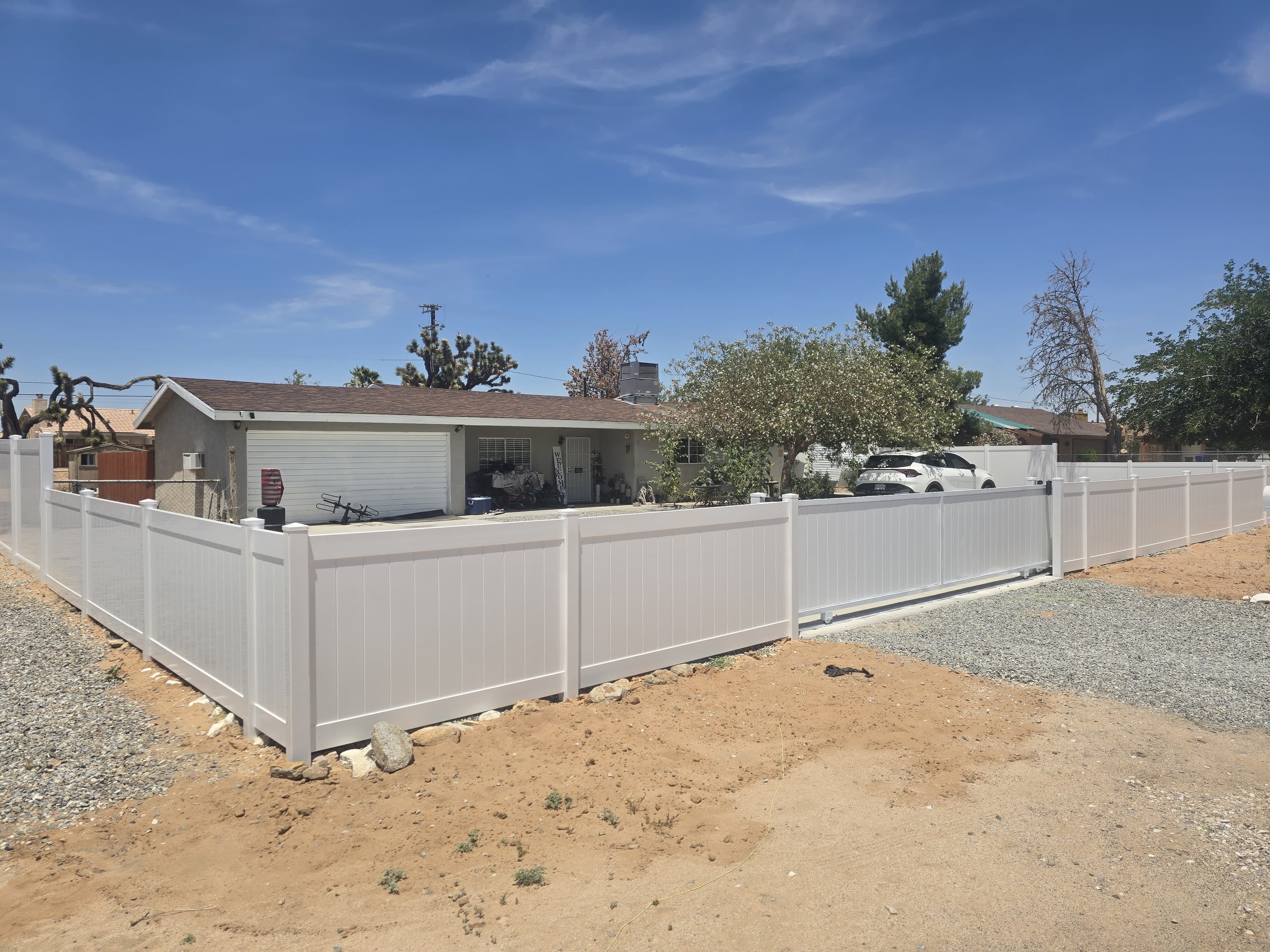 White vinyl fence panels and posts along a backyard boundary