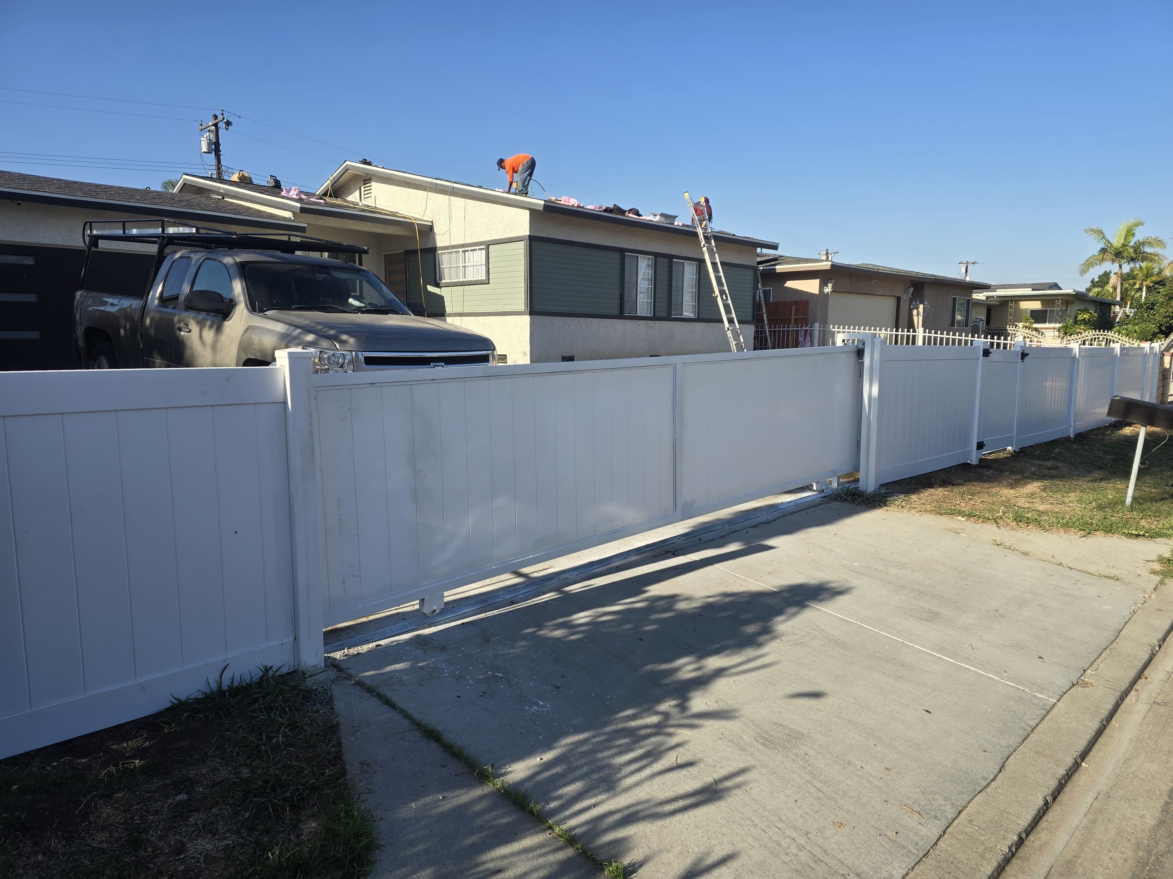 White vinyl fence and gate section near a residential front yard