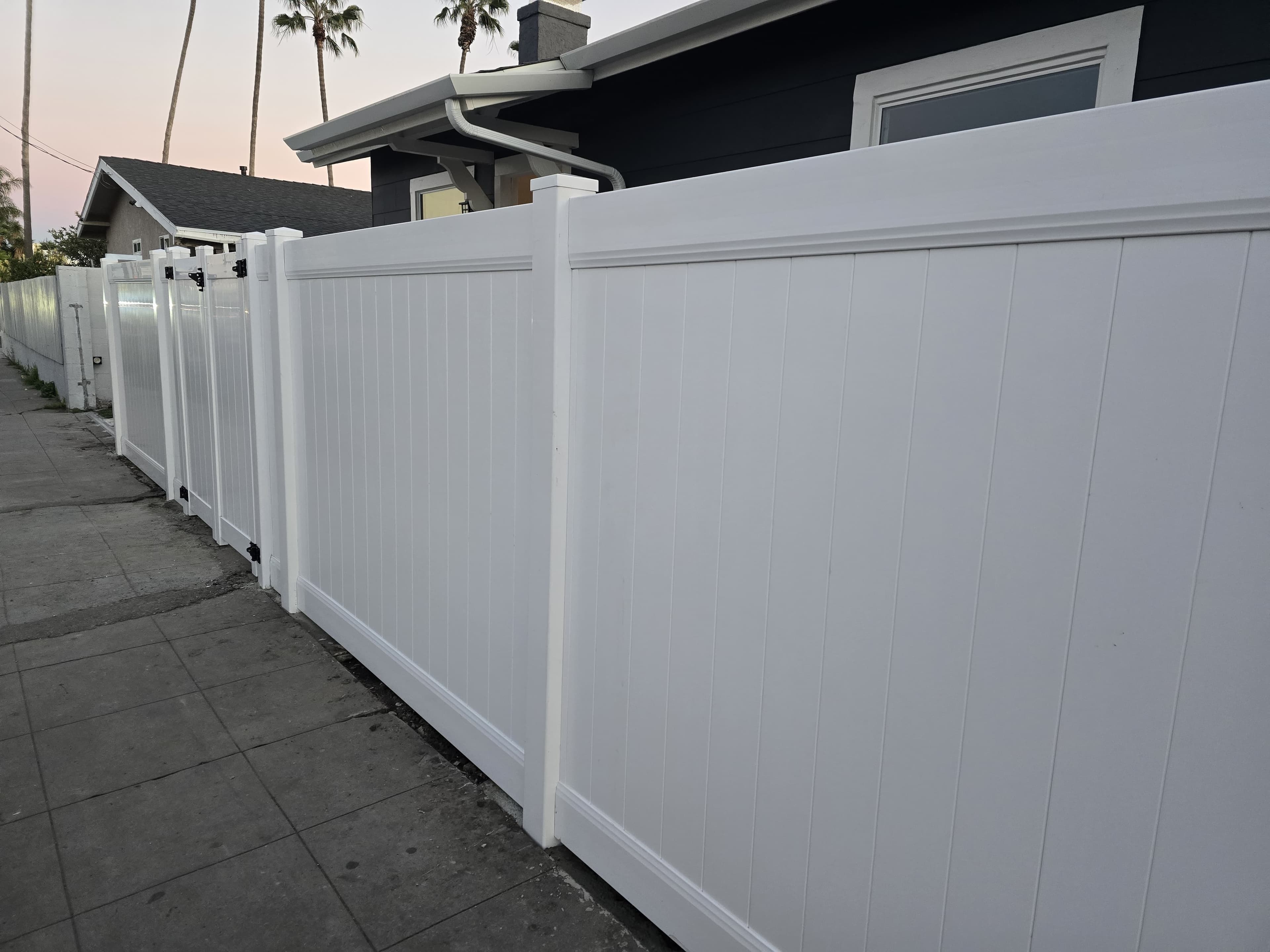 Close view of white vinyl privacy fence panels and posts