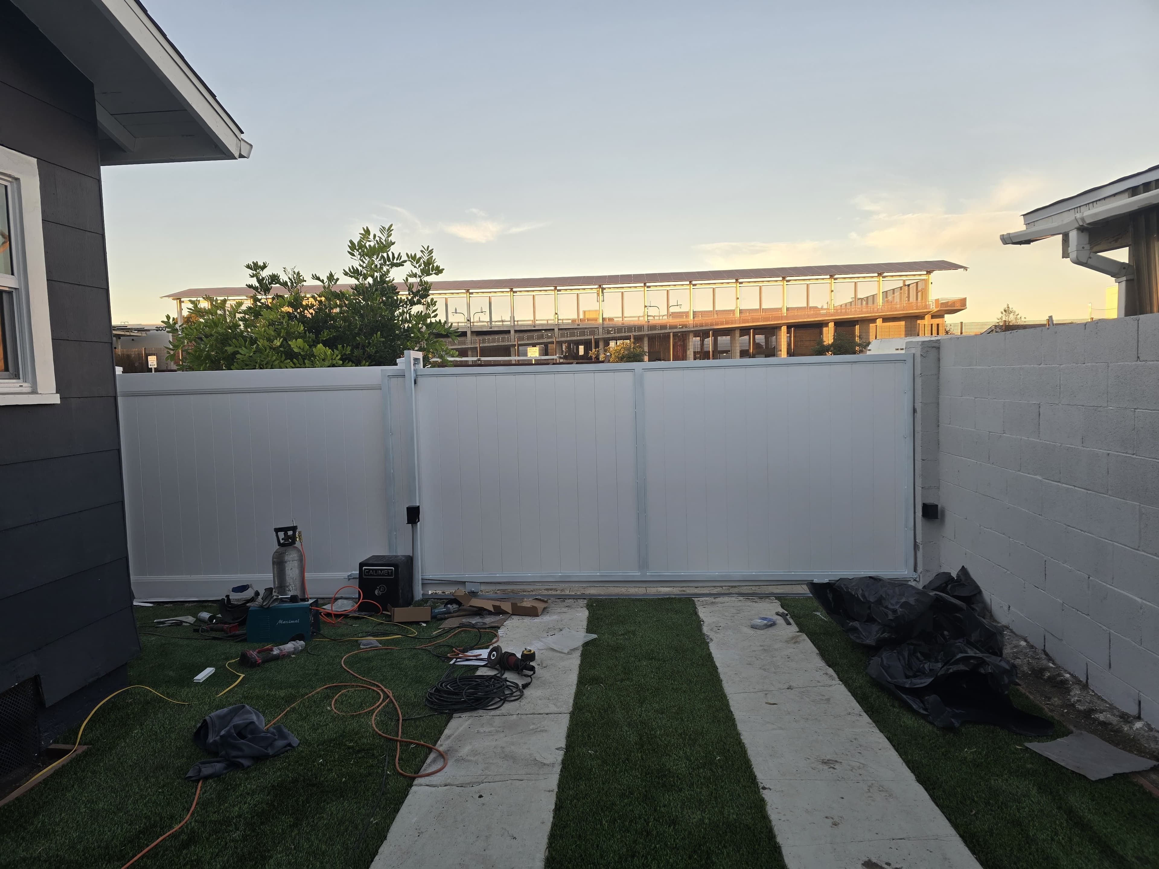 Wide view of white vinyl privacy gate and fence from inside the yard