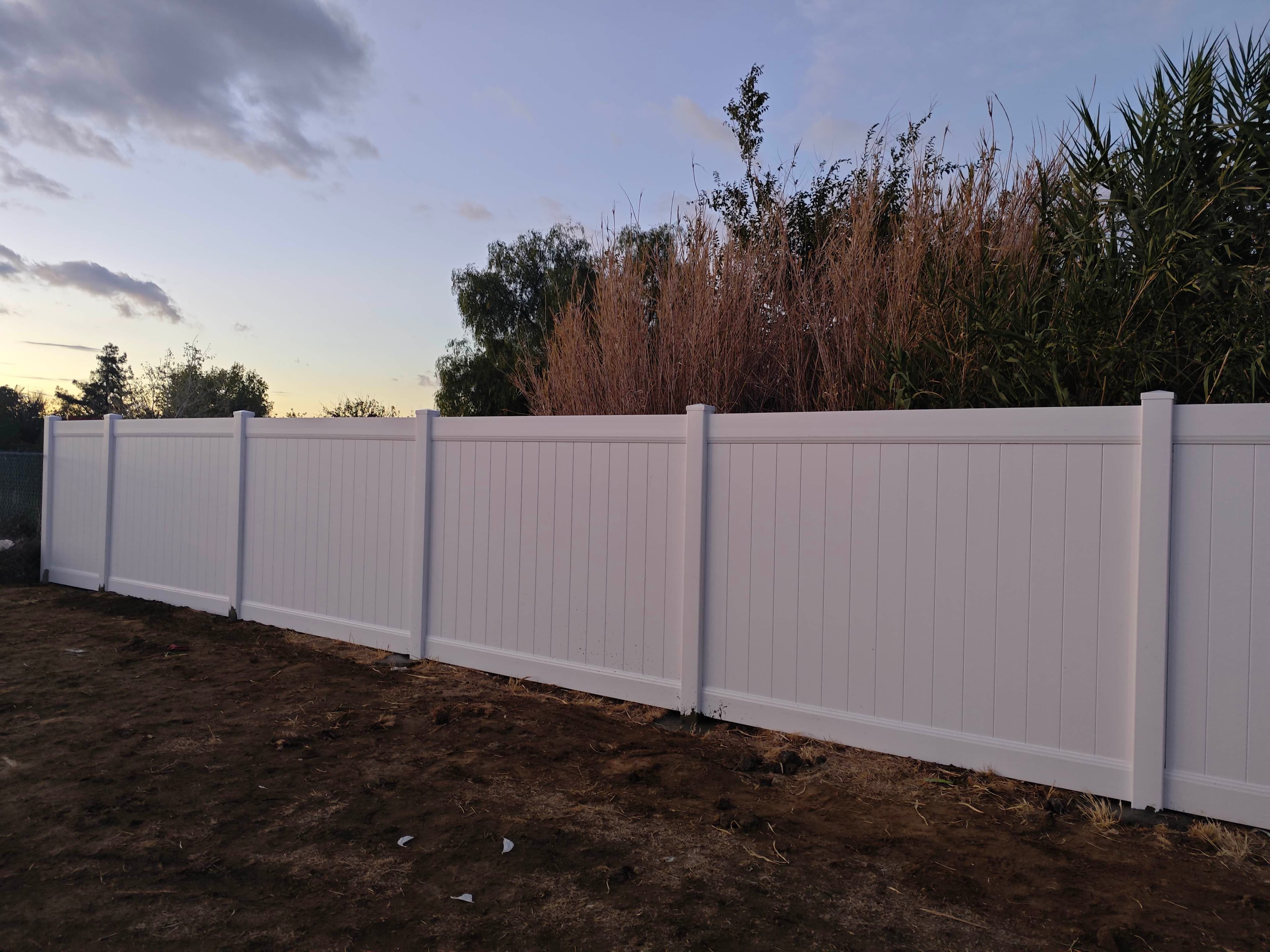 Corner section of a white vinyl privacy fence