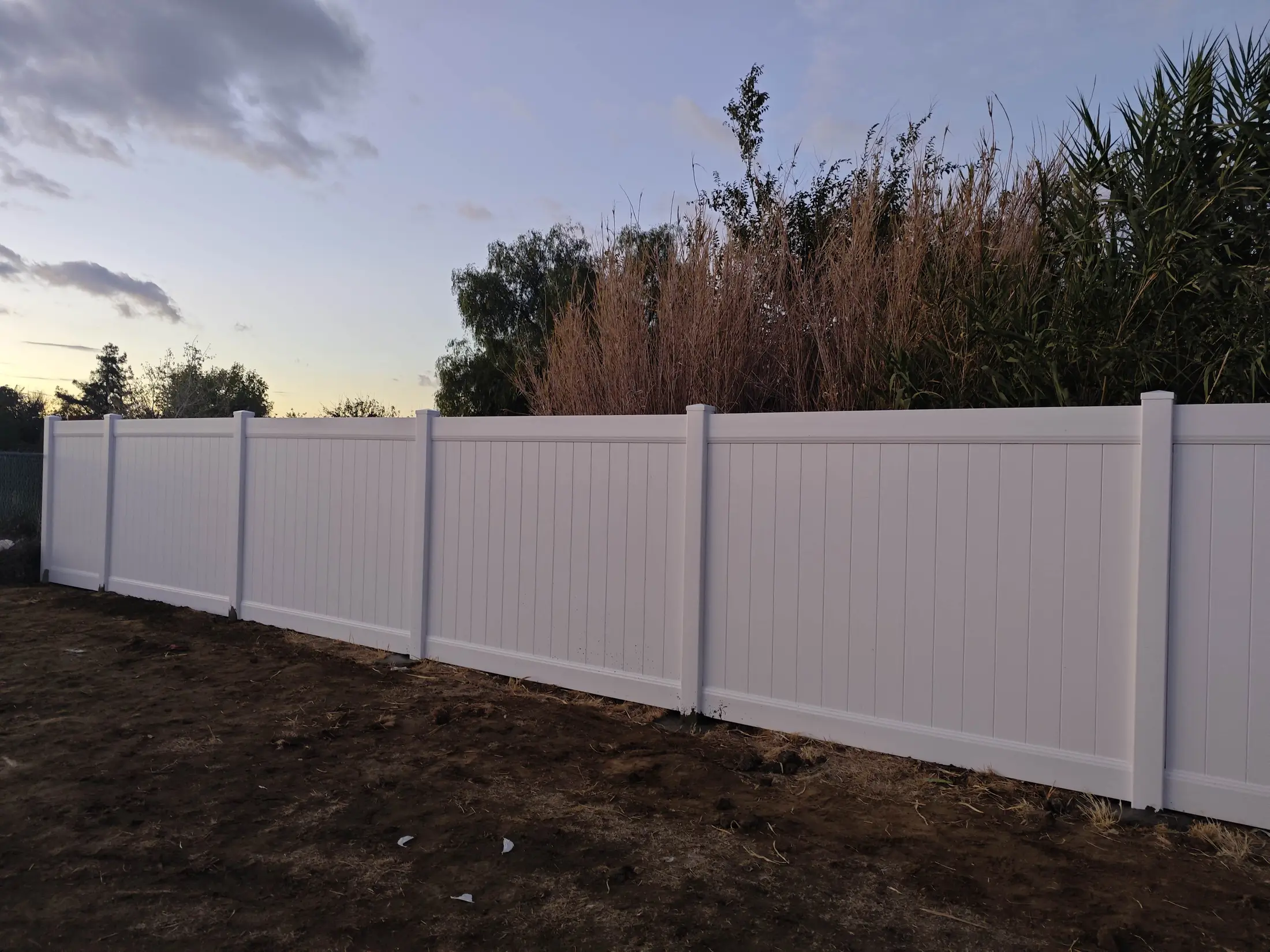 Corner section of a white vinyl privacy fence